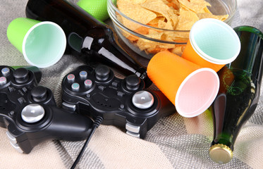 Black game controllers and bowl with snacks