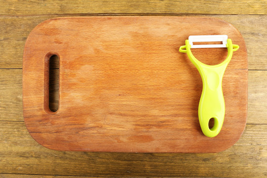 Vegetable peller and cutting board on wooden table