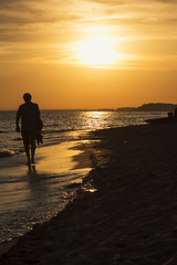Uomo che cammina su spiaggia al tramonto