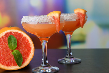 Grapefruit cocktail in glasses on bright background
