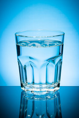 Glass of water isolated on blue background.
