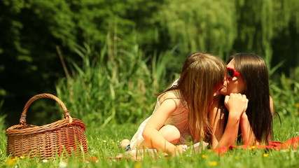Little daughter kissing her mother on the meadow - Powered by Adobe