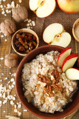 Tasty oatmeal with nuts and apples on wooden table
