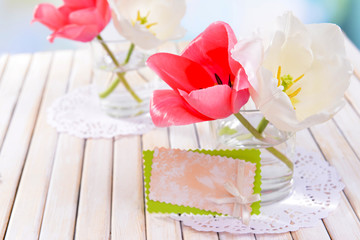 Beautiful tulips in bucket in vase on table on light background