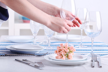 Woman laying table in room
