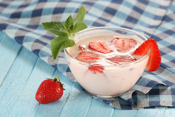 strawberry with yogurt in a glass bowl on a wooden board