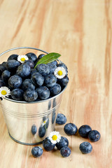 Blueberries in a bucket with daisy flowers