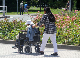 Mujer paseando a una persona anciana en silla de ruedas