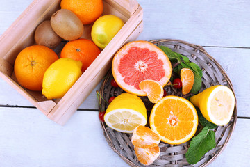 Fresh citrus fruits with green leaves in wooden box
