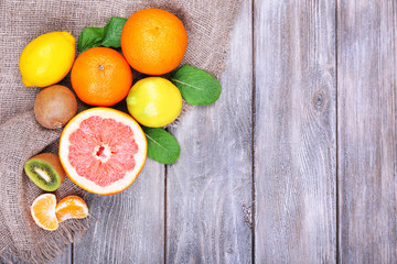 Fresh exotic fruits with green leaves on color wooden
