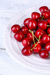Sweet cherries on plate on wooden background