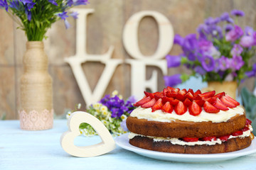 Strawberry cake with wildflowers and decorative letters on
