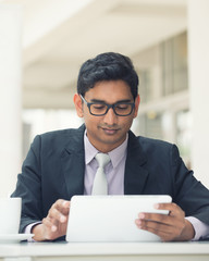 young indian business man with a tablet computer and coffee at a