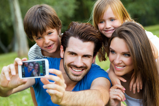 Happy young family taking selfies with her smartphone in the par