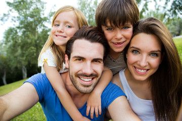 Fototapeta premium Happy young family taking selfies with her smartphone in the par