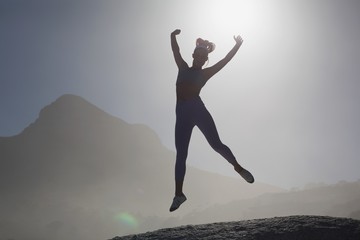 Fototapeta premium Sporty blonde on the beach on a rock jumping