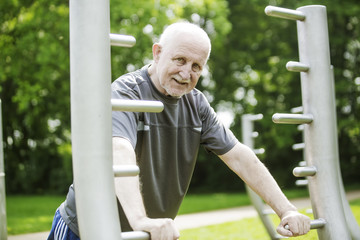 Obraz premium sportlicher senior trainiert an Fitnessgeräten im Park
