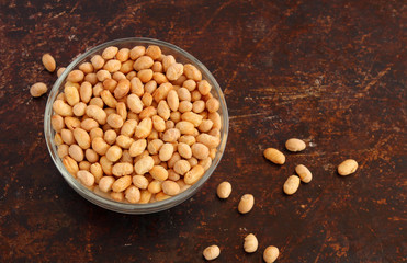 Roasted soy beans in bowl on brown background