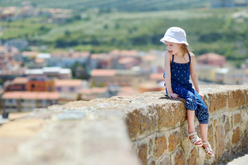Little girl sitting on a wall enjoying a view