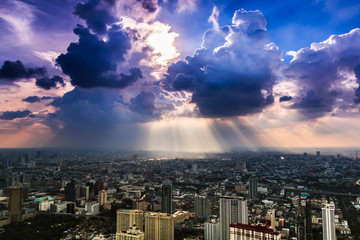 Fototapeta premium Rays of light shining through dark clouds in the Bangkok city