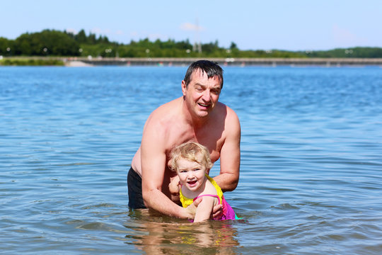Father and little daughter swimming in the lake on summer day