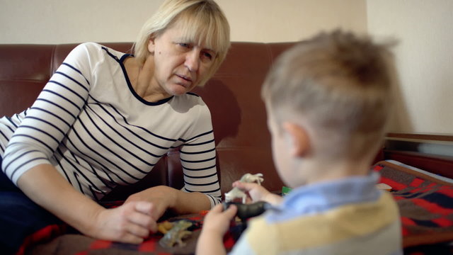 Grandmother and granson playing with toys on the sofa