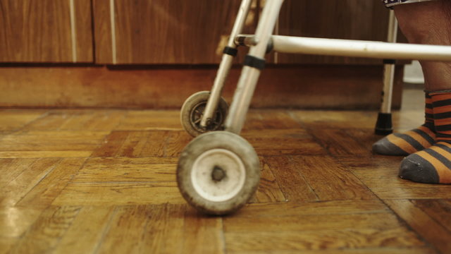 Senior woman walking slowly at home by means of walker