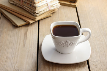 Cup of coffee on wooden table. Vintage books in the background