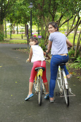 Obraz premium Woman and young girl on bikes outdoors smiling
