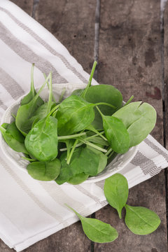 Fresh spinach in a bowl on wooden background