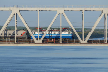 blue electric locomotive passing the bridge over the riv