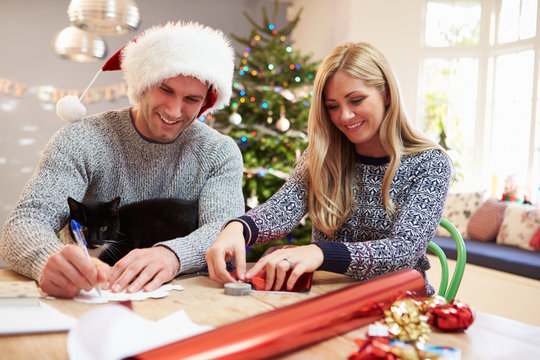 Couple Wrapping Christmas Gifts At Home