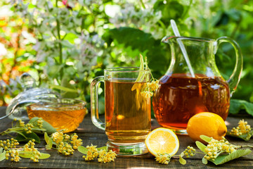 Herbal tea in a glass cup, fresh linden flowers on wooden table