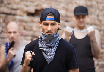 three dangerous gangster standing outside.