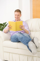 Smiling relaxed man reading book.
