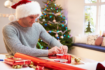 Obraz na płótnie Canvas Man Wrapping Christmas Gifts At Home