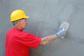 Worker making facade, trowel and cement mortar