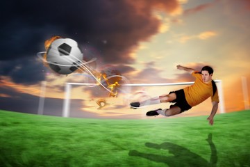 Fototapeta premium Composite image of football player in orange kicking