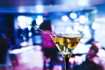 glass with martini and green olives