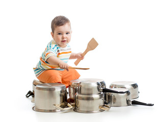 young boy using wooden spoons to bang pans drumset