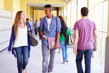 Group Of High School Students Walking Along Hallway