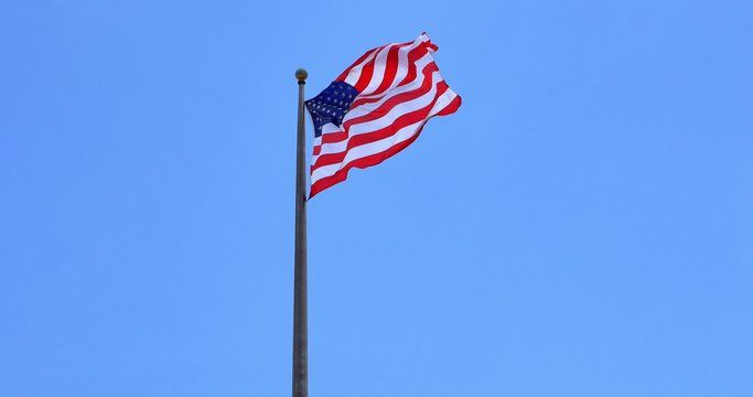 4K American flag - star and stripes floating over a blue sky 
