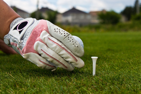 Close-up of a gloved hand of a female golfer placing golf ball o