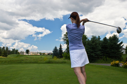 Female golfer swinging her golf club