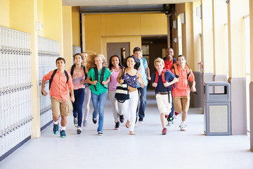 Group Of High School Students Running Along Corridor