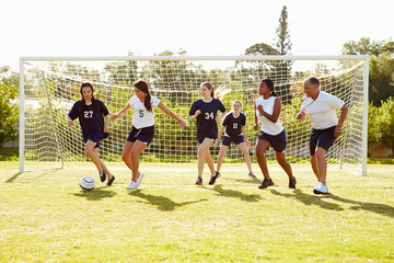 Obraz na płótnie Canvas Members Of Female High School Soccer Playing Match