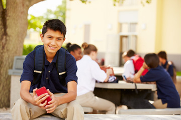 Male High School Student Using Phone On School Campus