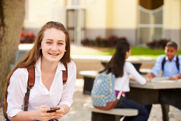 Fototapeta na wymiar Female High School Student Using Phone On School Campus