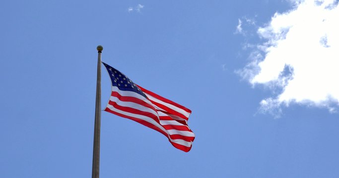 4K American flag - star and stripes floating over a blue sky 