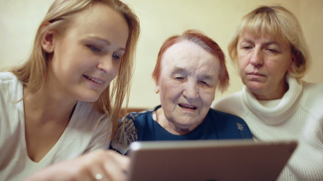 Woman with pad showing photos or video to her mother and